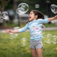 A little girl that is playing with bubbles