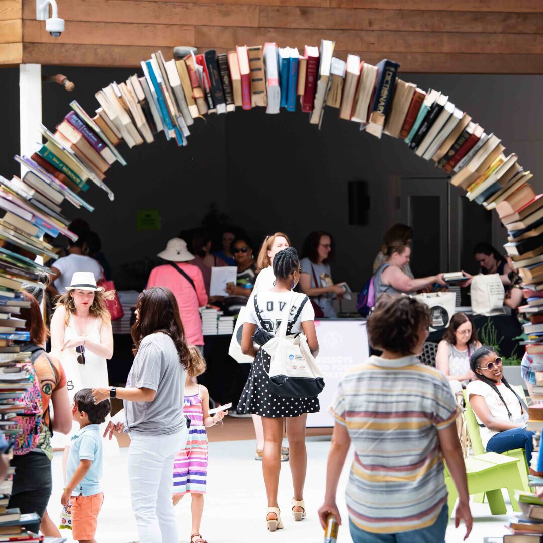A group of people standing around in front of books.